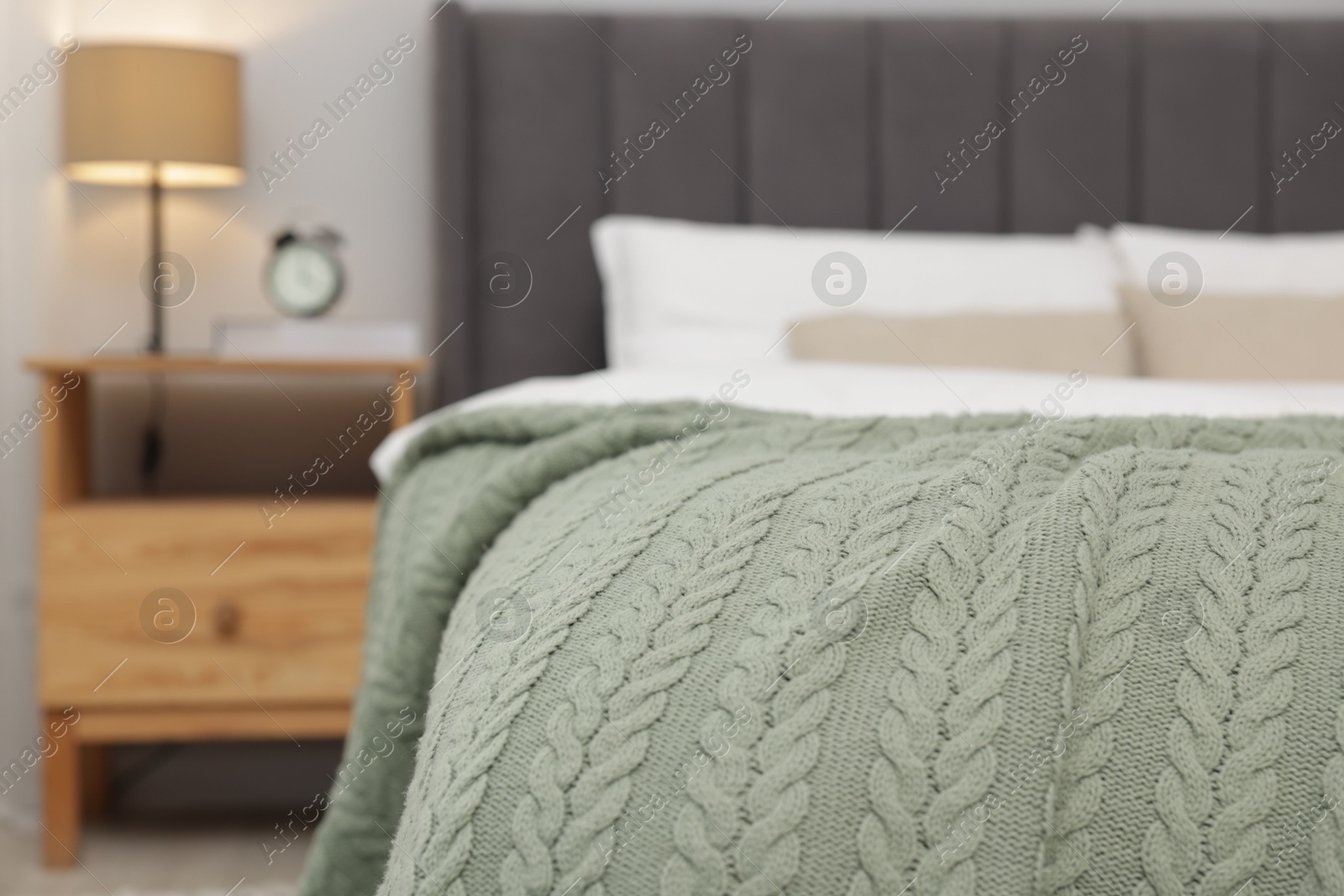 Color woolen blanket on bed indoors, closeup Photo of Color woolen blanket on bed indoors, closeup