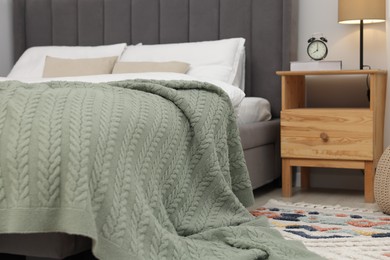 Photo of Green woolen blanket on bed in room