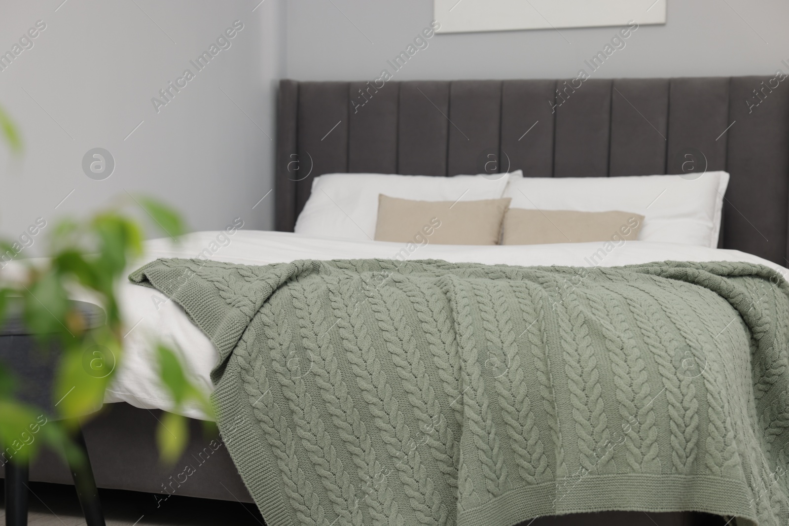 Green woolen blanket on bed in room Photo of Green woolen blanket on bed in room
