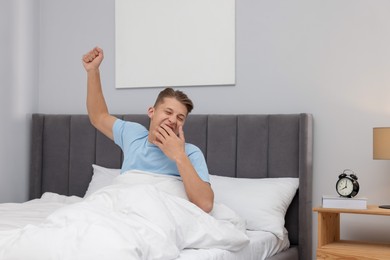 Photo of Man stretching in comfortable bed at home