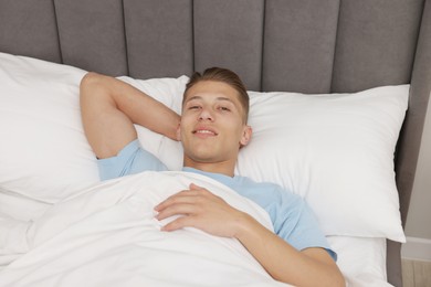 Photo of Man lying in comfortable bed at home, above view