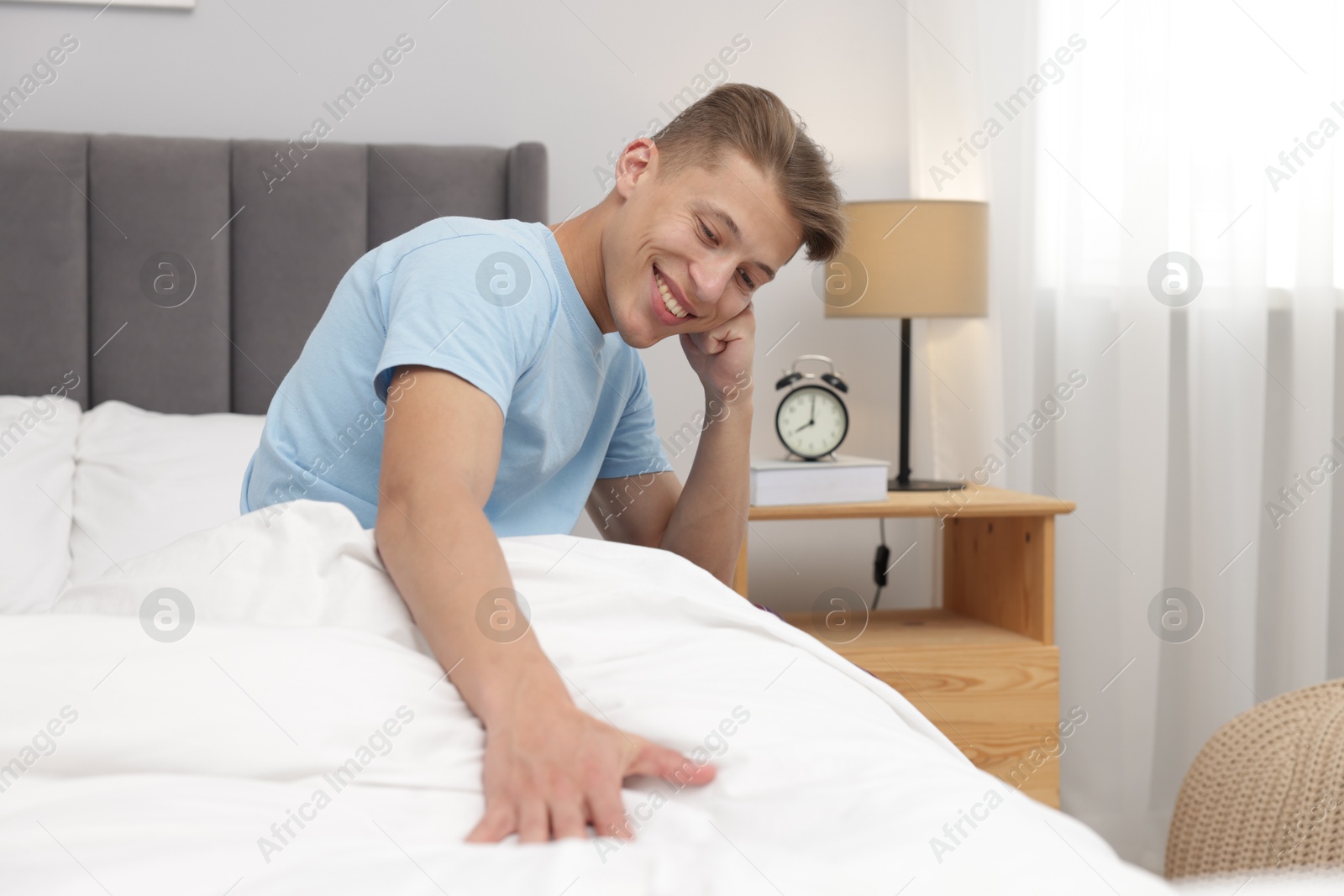 Happy man sitting on comfortable bed at home Photo of Happy man sitting on comfortable bed at home