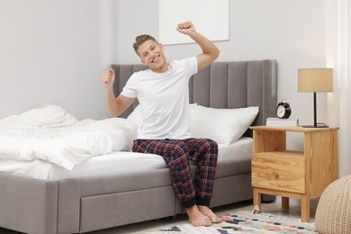 Photo of Man stretching on comfortable bed at home