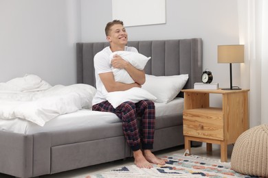 Photo of Man with pillow sitting on comfortable bed at home
