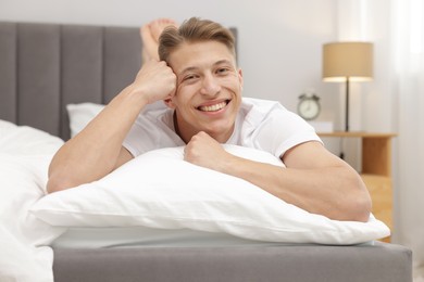 Photo of Happy man lying on comfortable bed at home