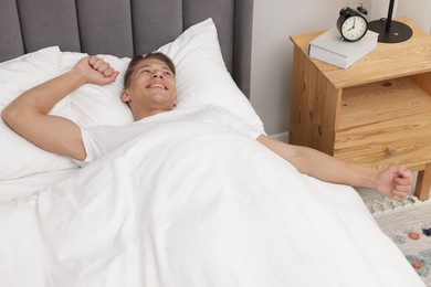 Photo of Man lying in comfortable bed at home, above view
