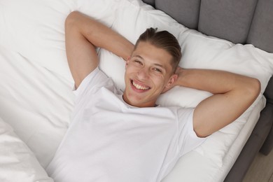 Photo of Man lying in comfortable bed at home, top view