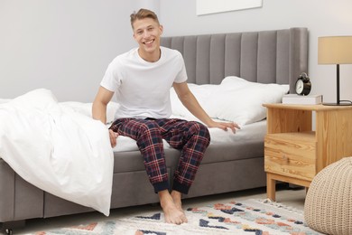 Photo of Happy man sitting on comfortable bed at home