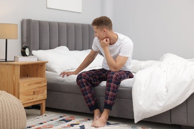 Photo of Happy man sitting on comfortable bed at home