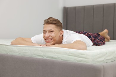 Photo of Happy man lying on soft mattress at home