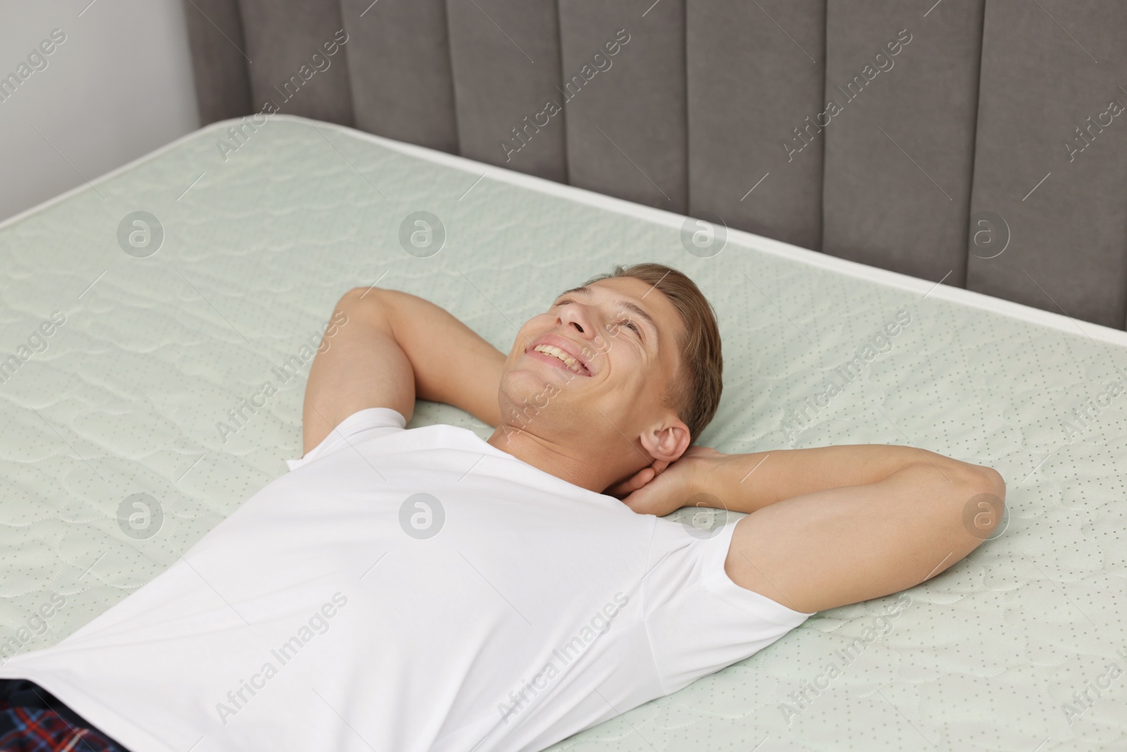 Happy man lying on soft mattress at home, above view Photo of Happy man lying on soft mattress at home, above view