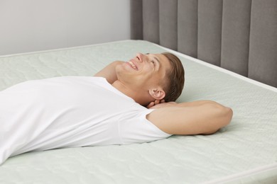 Photo of Happy man lying on soft mattress at home