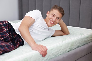 Photo of Happy man lying on soft mattress at home