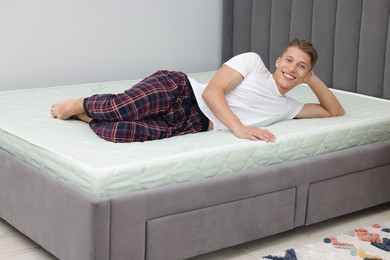 Photo of Happy man lying on soft mattress at home
