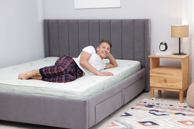 Photo of Happy man lying on soft mattress at home