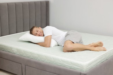 Photo of Happy man lying on soft mattress at home