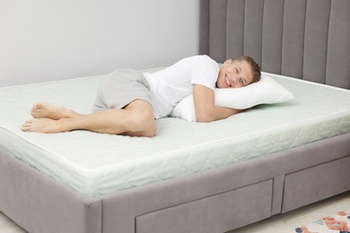 Photo of Happy man lying on soft mattress at home