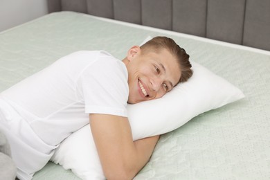 Photo of Happy man lying on soft mattress at home