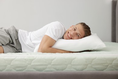 Photo of Happy man lying on soft mattress at home