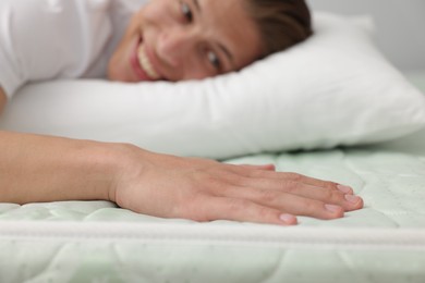 Photo of Happy man lying on soft mattress at home, selective focus