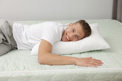 Photo of Happy man lying on soft mattress at home