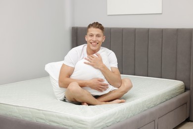 Photo of Man with pillow sitting on soft mattress at home
