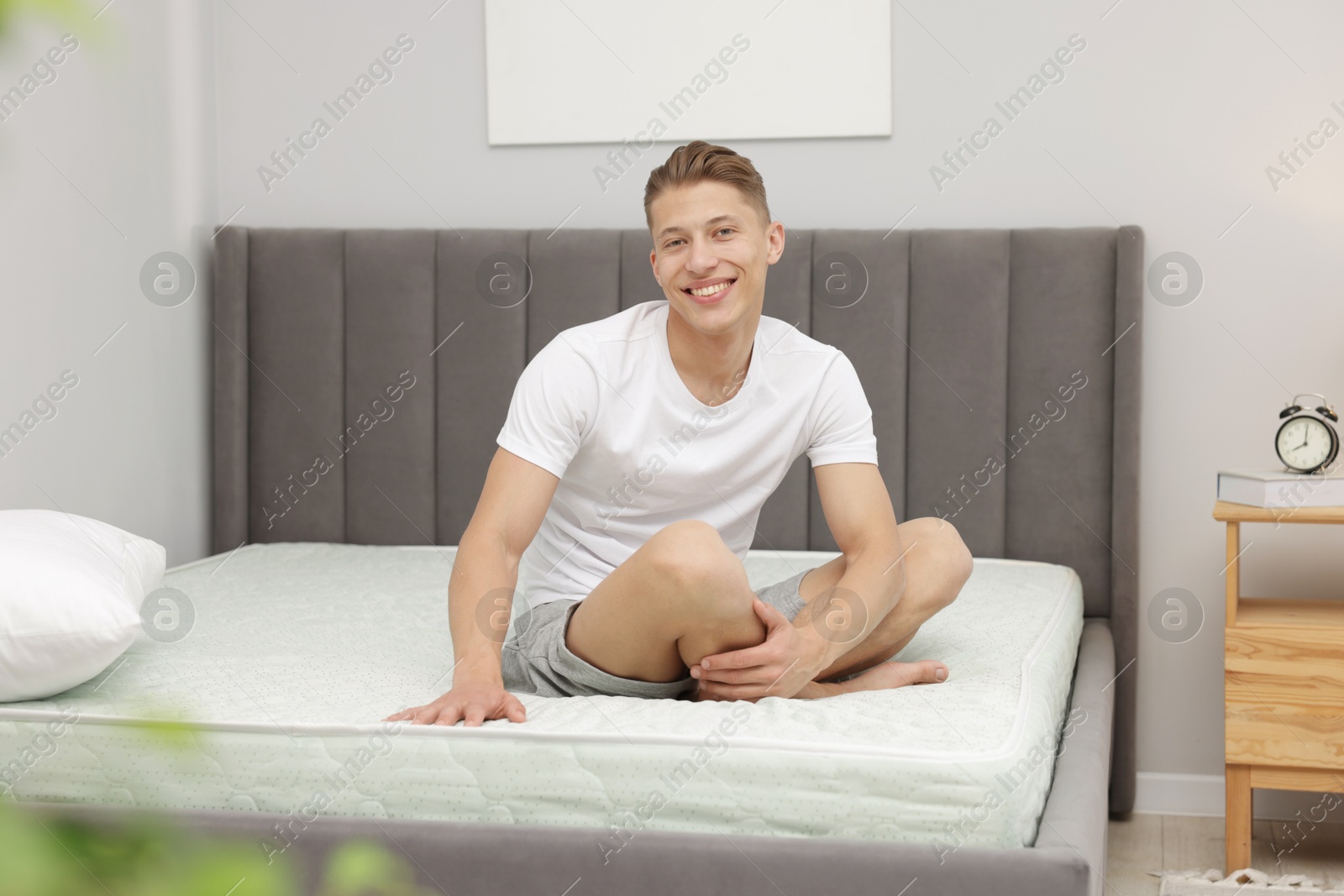 Man sitting on soft mattress at home Photo of Man sitting on soft mattress at home