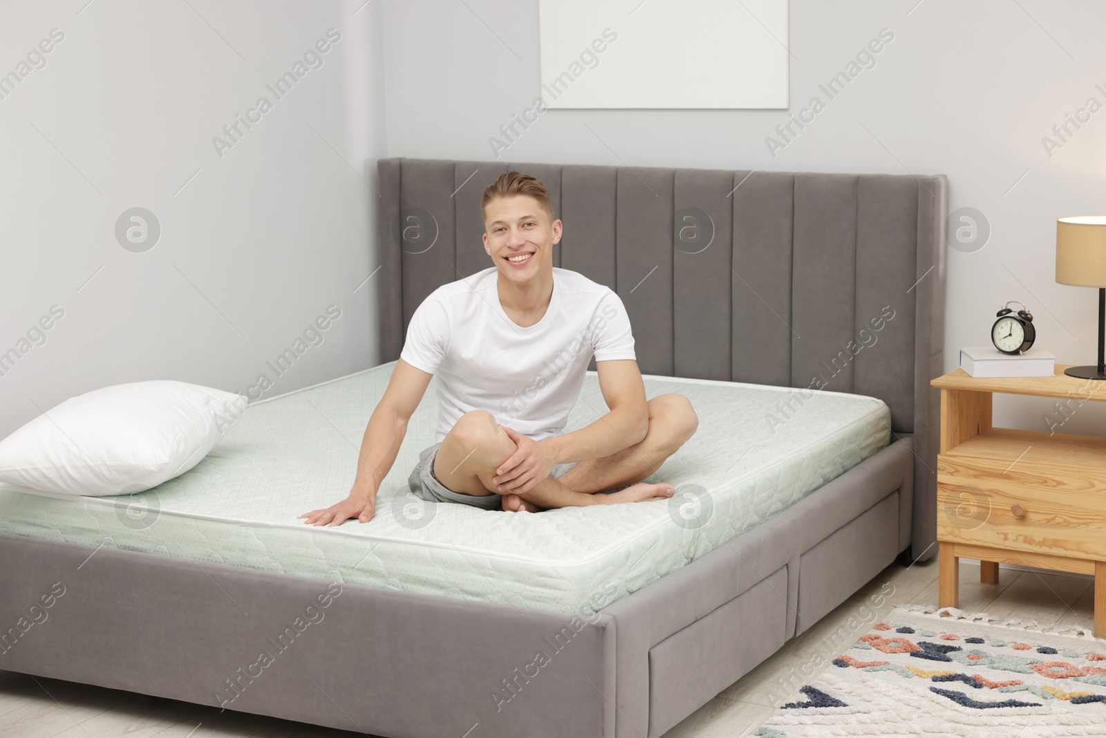 Man sitting on soft mattress at home Photo of Man sitting on soft mattress at home