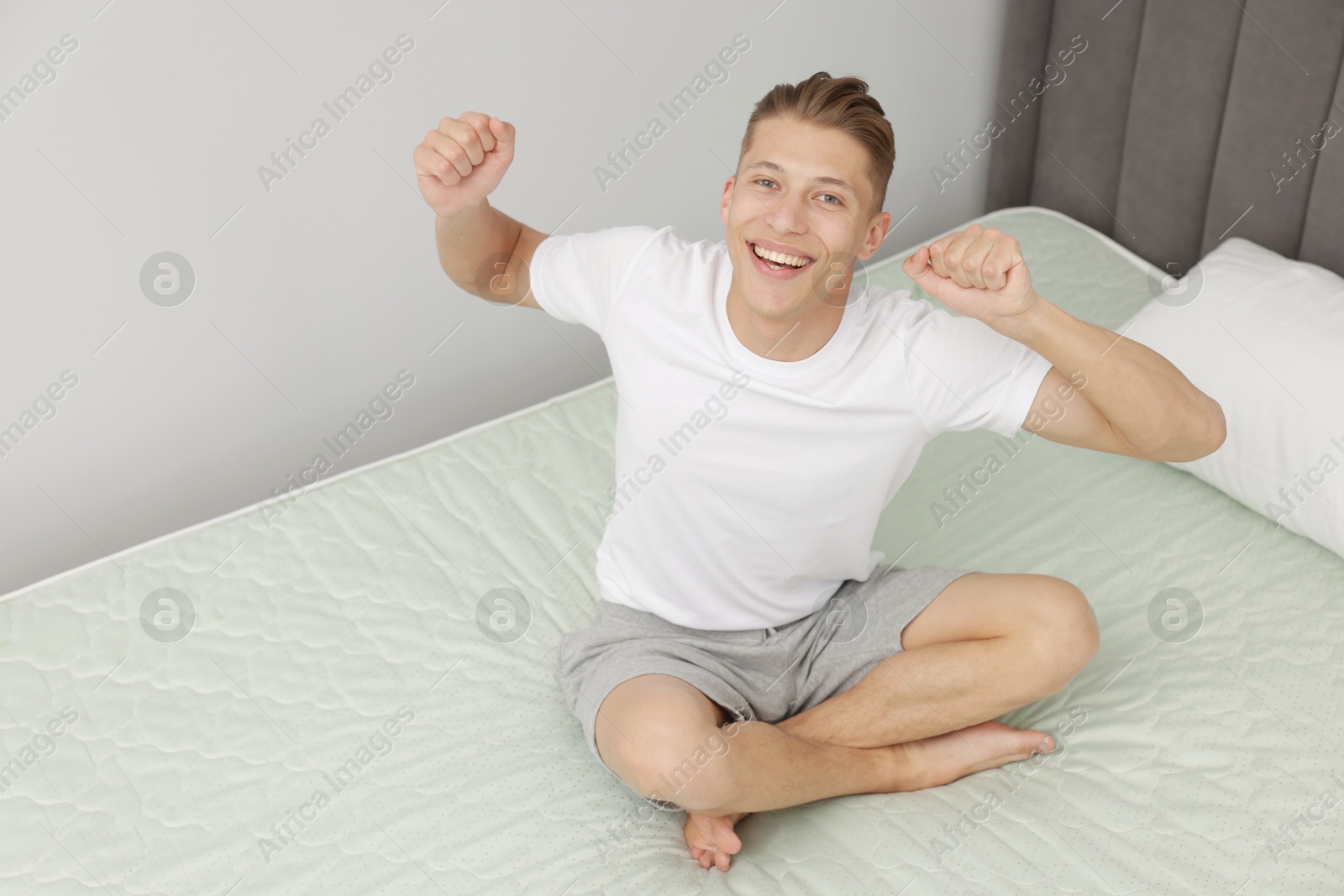 Man sitting on soft mattress at home, above view. Space for text Photo of Man sitting on soft mattress at home, above view. Space for text