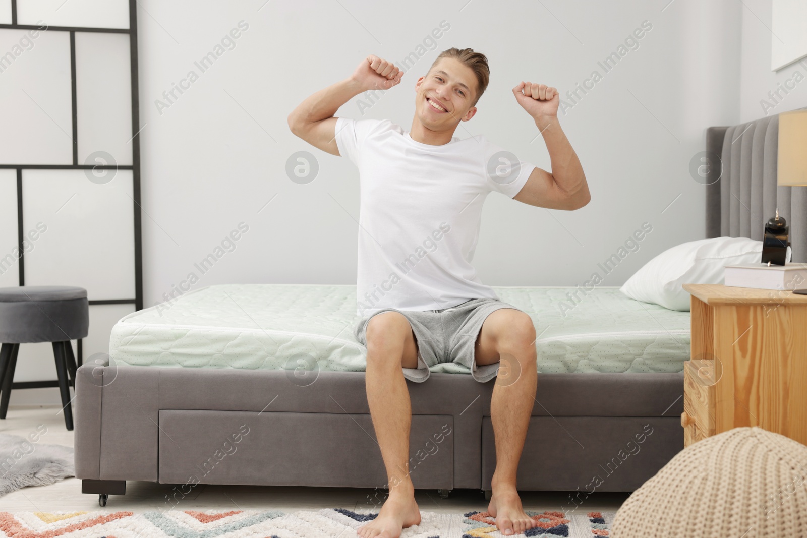Man sitting on soft mattress at home Photo of Man sitting on soft mattress at home
