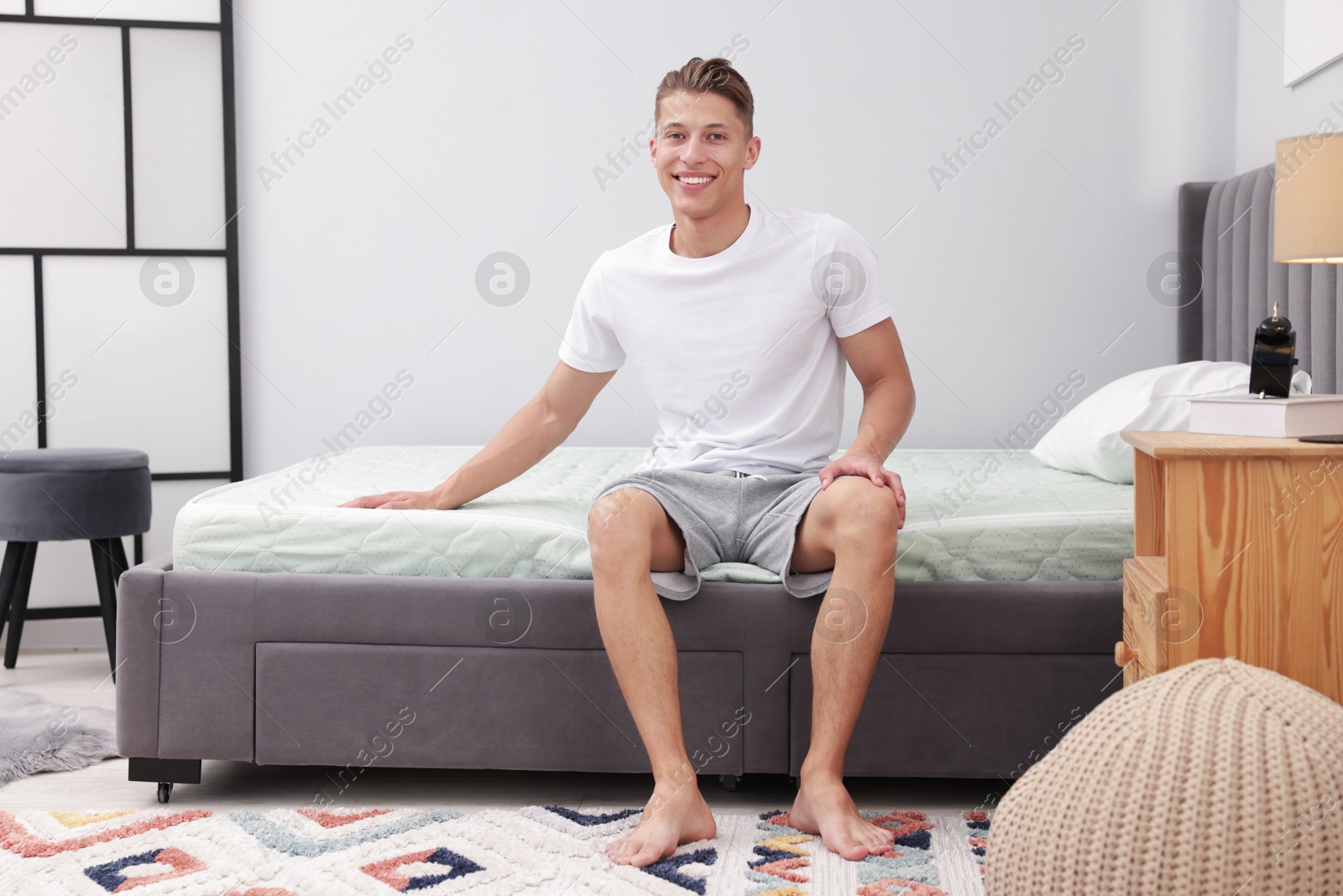 Man sitting on soft mattress at home Photo of Man sitting on soft mattress at home