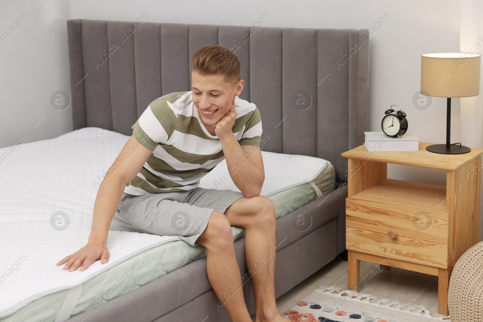 Man sitting on soft mattress at home Photo of Man sitting on soft mattress at home