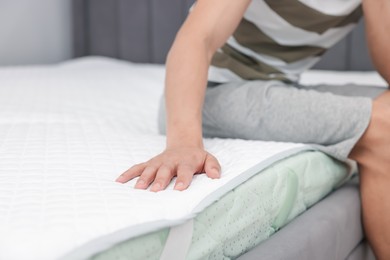 Photo of Man sitting on soft mattress at home, closeup. Space for text