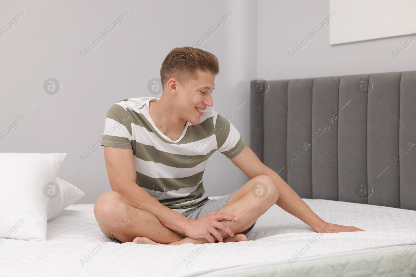 Photo of Happy man sitting on soft mattress at home