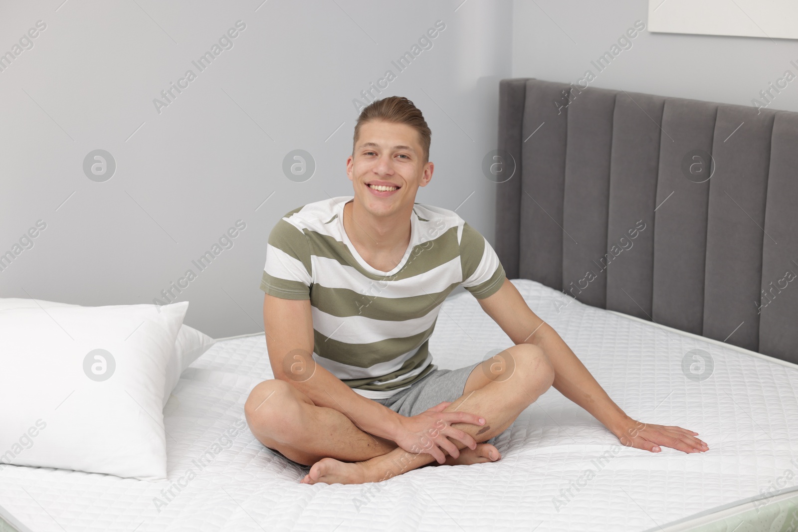 Happy man sitting on soft mattress at home Photo of Happy man sitting on soft mattress at home