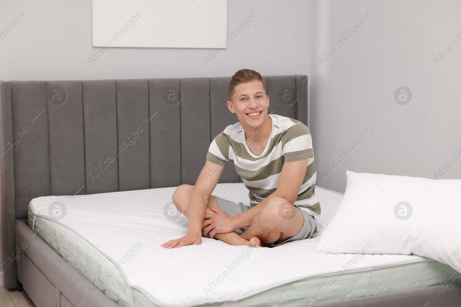 Photo of Happy man sitting on soft mattress at home