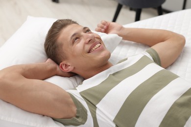 Photo of Happy man lying on soft mattress at home