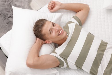 Photo of Happy man lying on soft mattress at home, top view