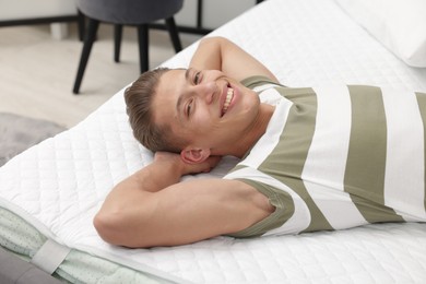 Photo of Happy man lying on soft mattress at home