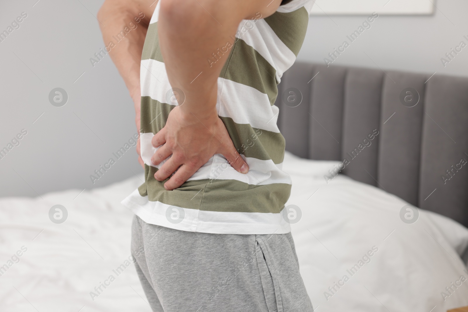 Man suffering from back pain after sleeping on uncomfortable mattress at home, closeup Photo of Man suffering from back pain after sleeping on uncomfortable mattress at home, closeup