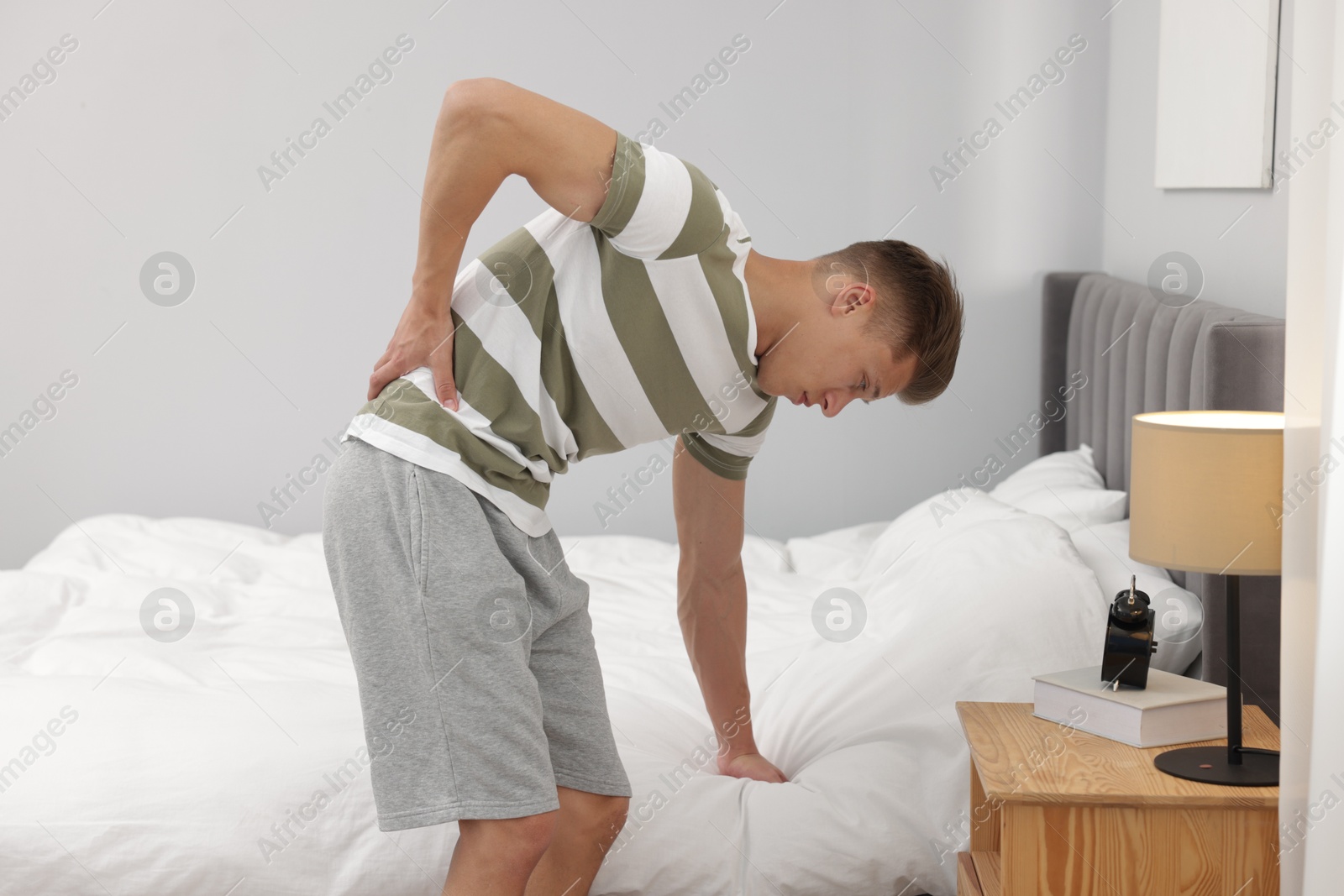 Man suffering from back pain after sleeping on uncomfortable mattress at home Photo of Man suffering from back pain after sleeping on uncomfortable mattress at home