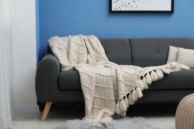 Photo of Beige woolen blanket and pillows on sofa indoors