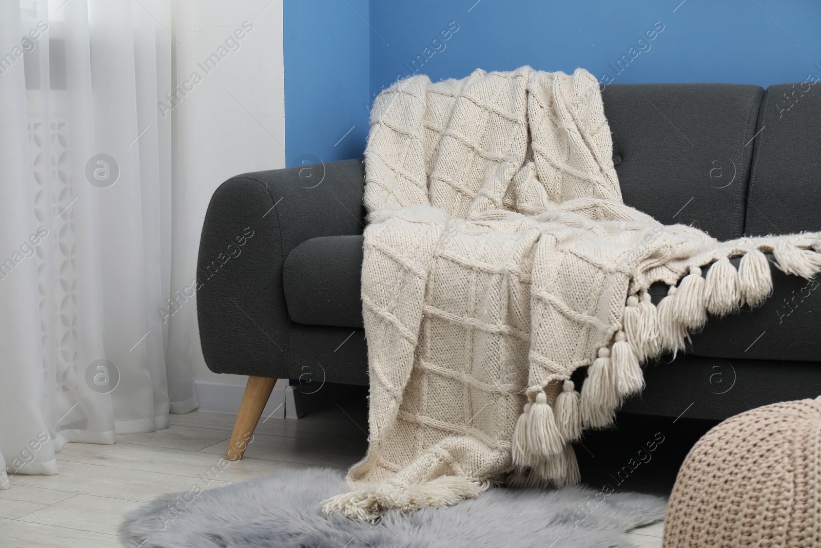 Beige woolen blanket on sofa in living room Photo of Beige woolen blanket on sofa in living room