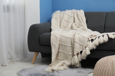 Photo of Beige woolen blanket on sofa in living room