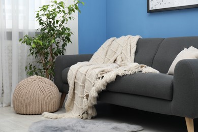 Photo of Beige woolen blanket on sofa in living room