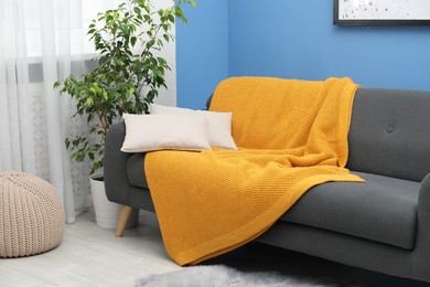Photo of Orange woolen blanket and pillows on sofa indoors