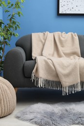 Photo of Beige woolen blanket on sofa in living room