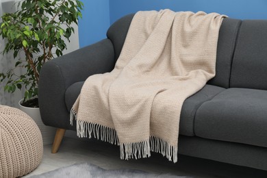 Photo of Beige woolen blanket on sofa in living room