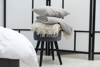 Photo of Woolen blankets and pillow on pouf indoors