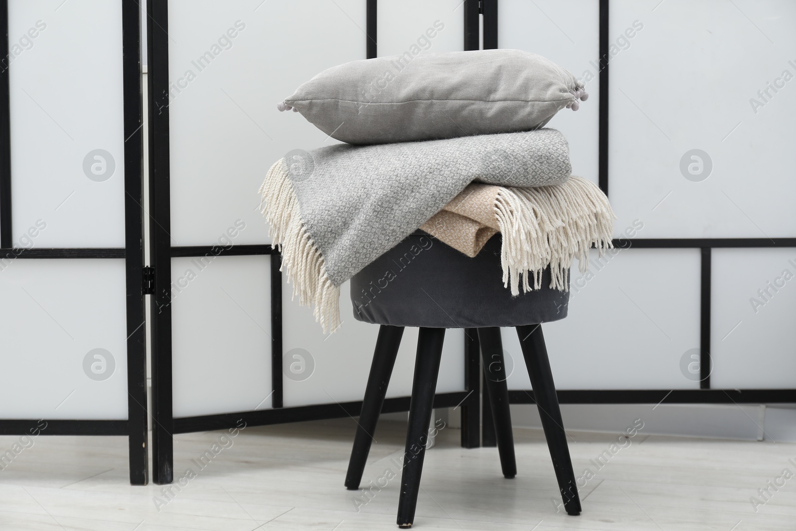 Woolen blankets and pillow on pouf indoors Photo of Woolen blankets and pillow on pouf indoors